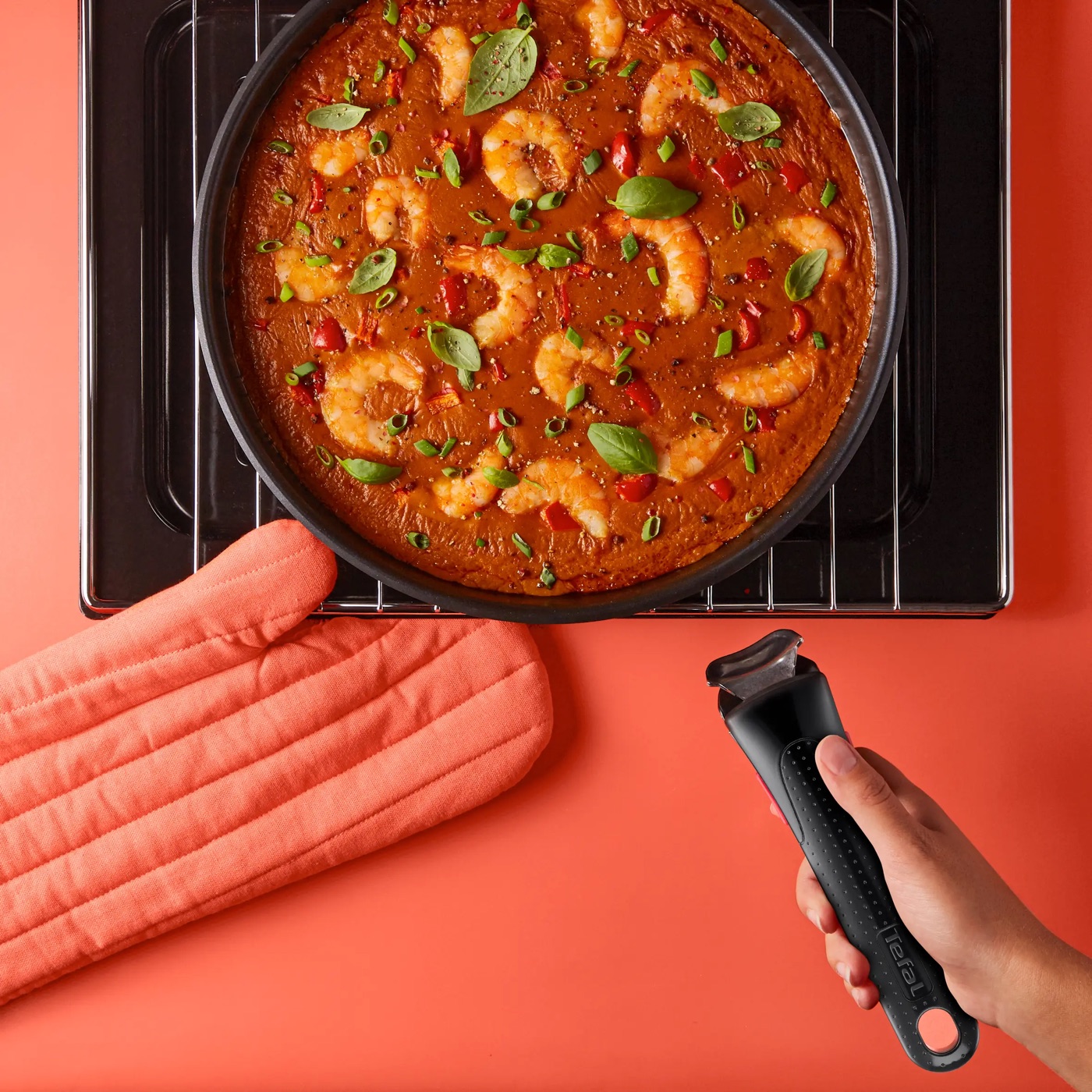 Sartén Ingenio con langostinos saliendo del horno y mano sujetando el mango extraíble